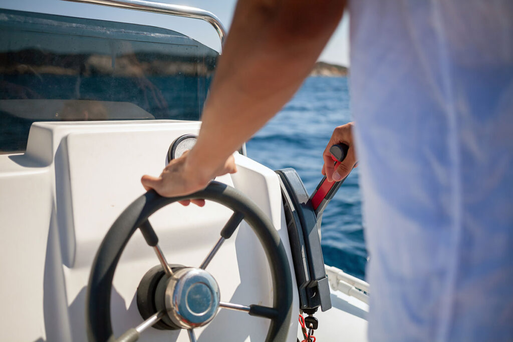 man holding steering wheel on boat